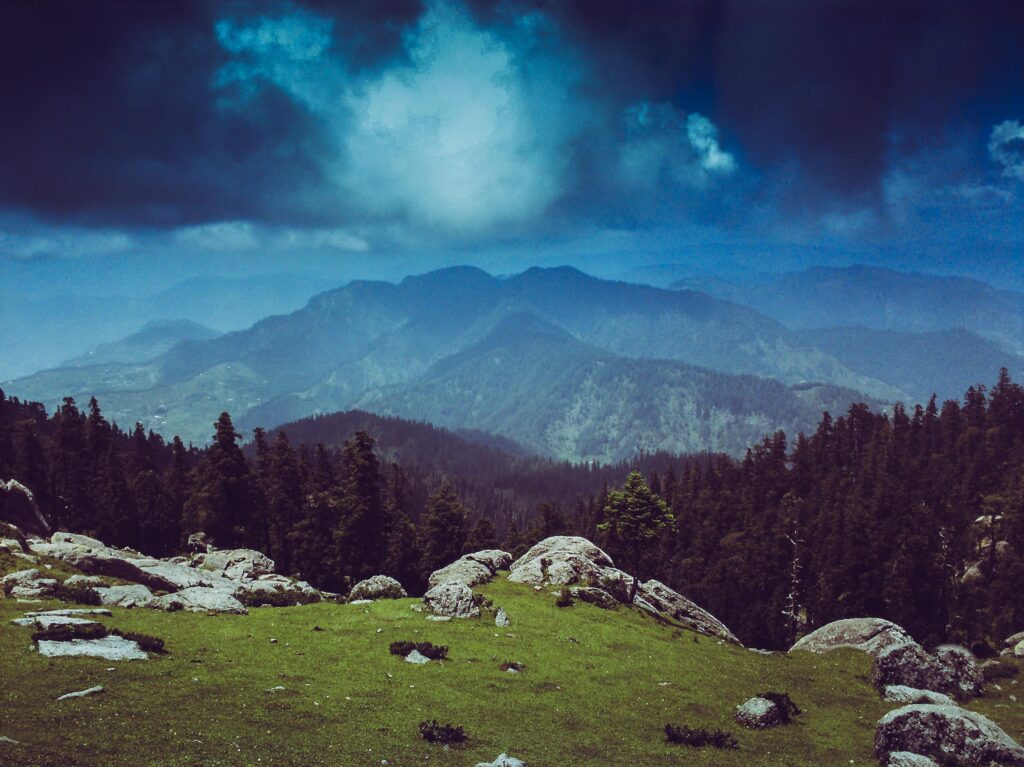 A breathtaking landscape view of Churdhar mountains with lush greenery and dramatic skies.
