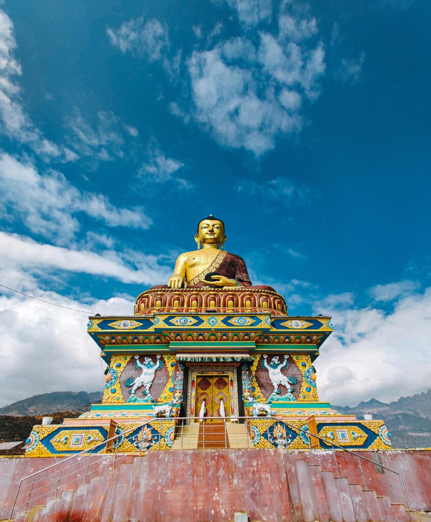 A stunning golden Buddha statue set against a clear blue sky in Tawang, showcasing vibrant colors and intricate details.