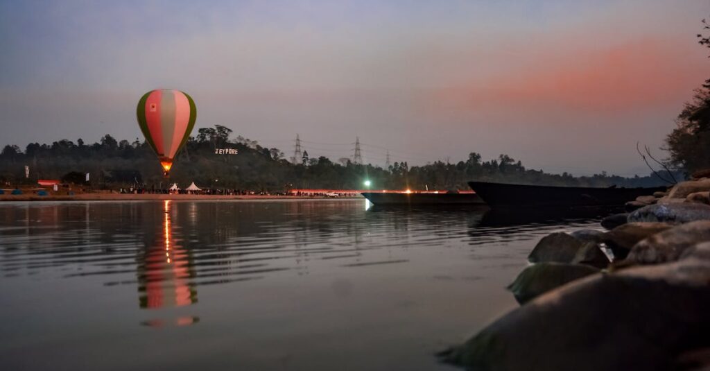A colorful hot air balloon is reflected on a tranquil lake at sunset, offering a scenic view in Arunachal Pradesh.