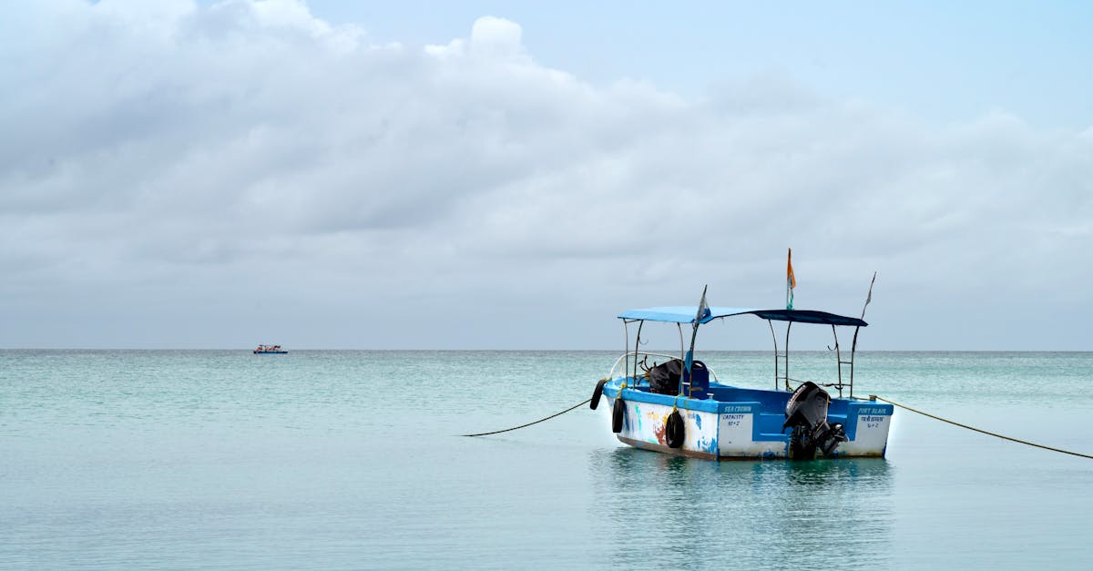 A solitary boat floats serenely on the calm Andaman Sea under a partially cloudy sky.