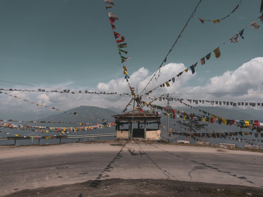 Colorful prayer flags on a mountain road in Tawang, offering a scenic Himalayan view.